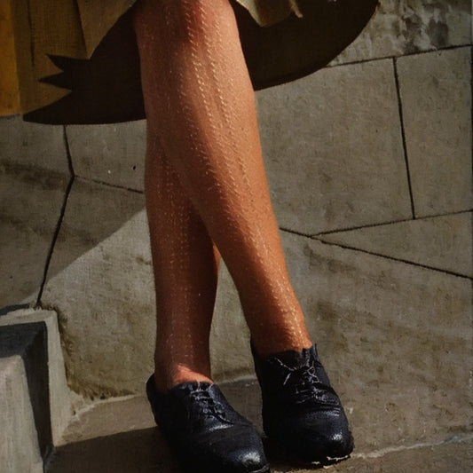 Person wearing black shoes on a stone pavement with knitted tights WW2