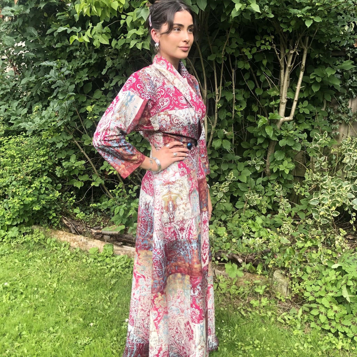 Photo of a girl stood outside, wearing 'Coachman Robe' in a bright pink patterned material.