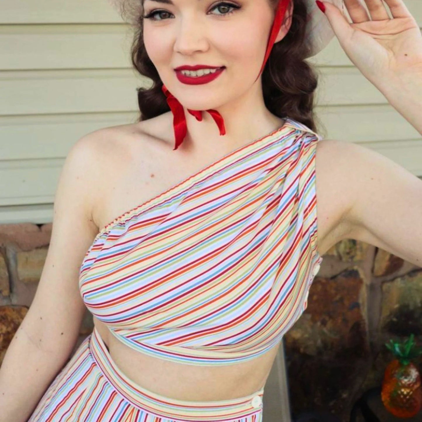 Woman wearing a colorful striped outfit with a red headband, posing outdoors.