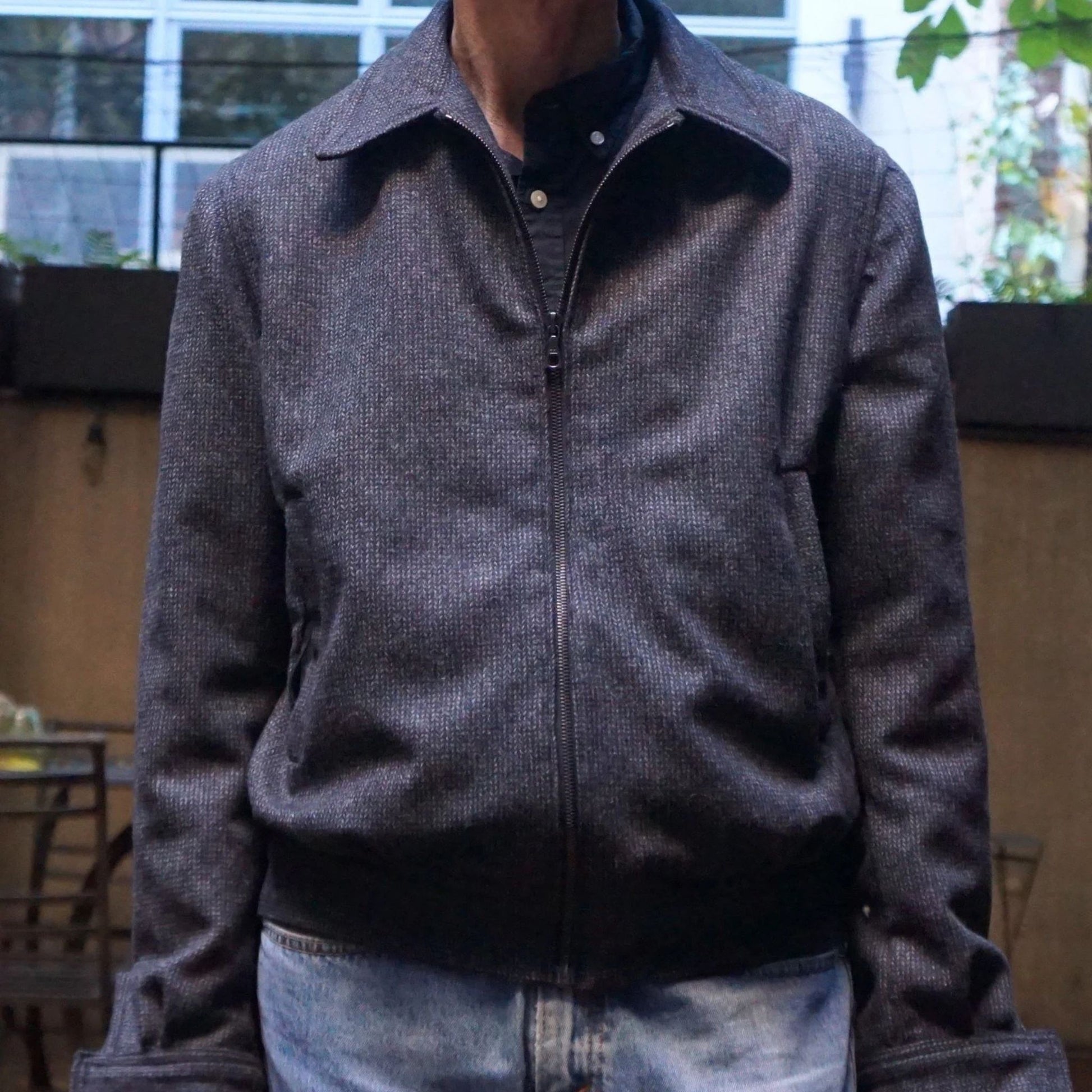 Person wearing a gray jacket with a blurred indoor background