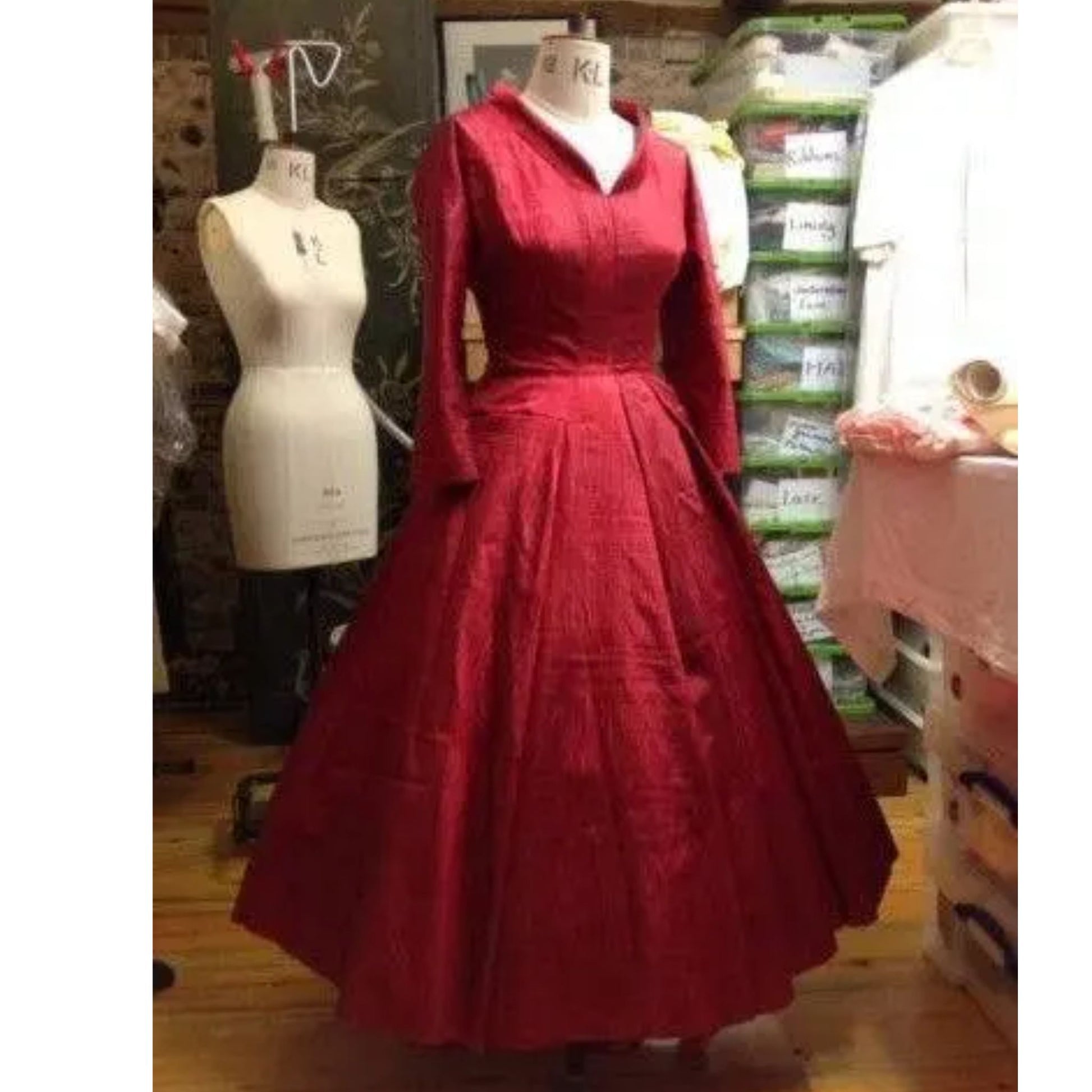 Red dress on a mannequin in a store setting with various items in the background