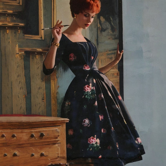 Woman in a dark floral dress holding a paintbrush in an artistic setting.