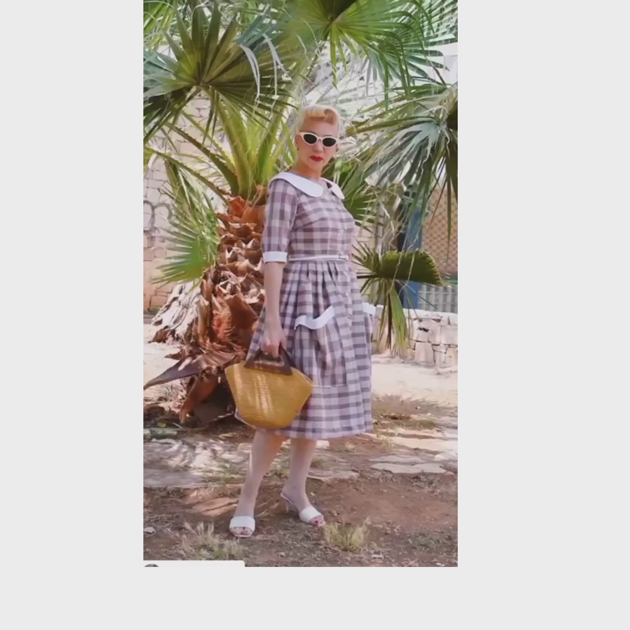 Blonde haired woman wearing a gingham brigette style dress made up from a sewing pattern.
