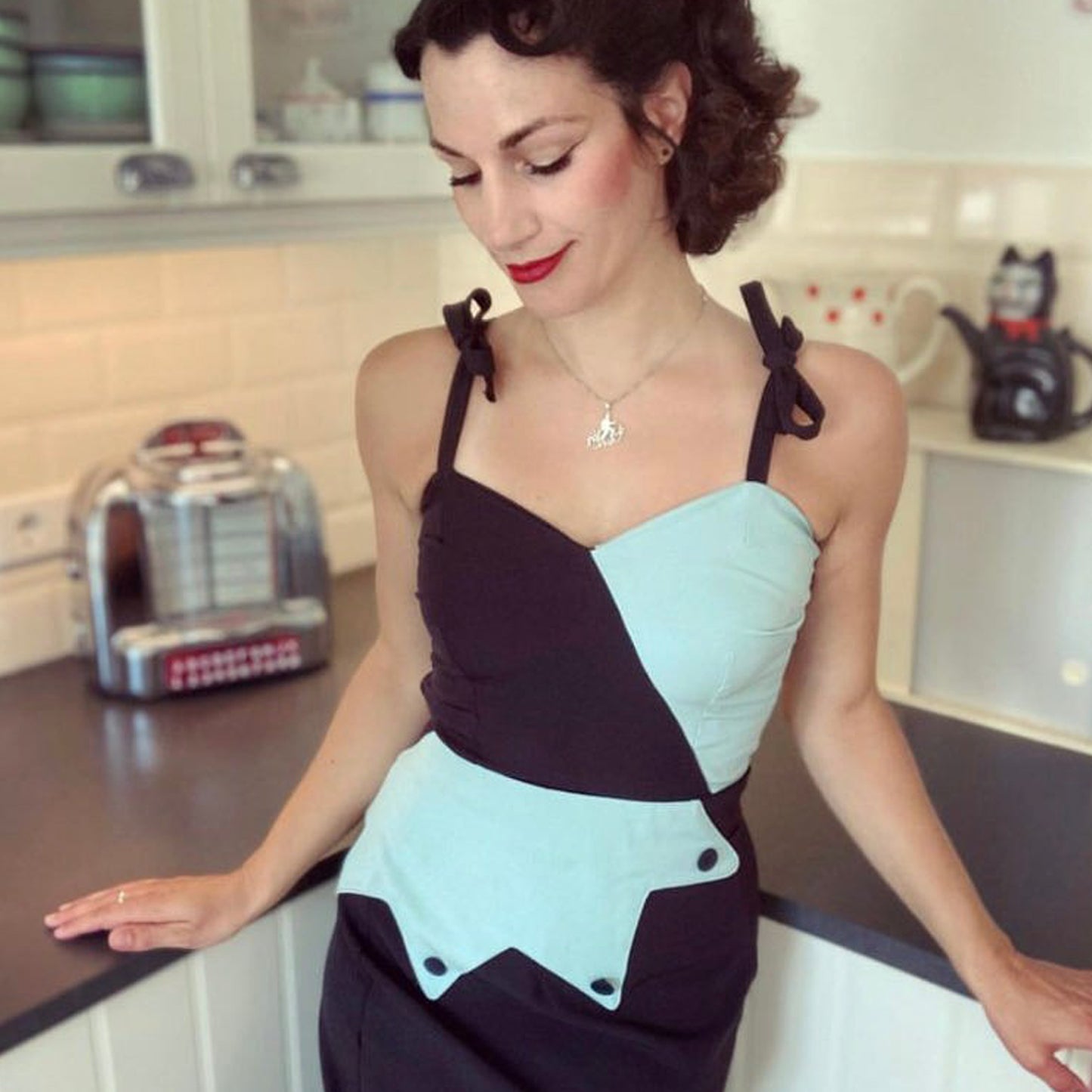 Woman wearing a black and light blue dress in a kitchen setting